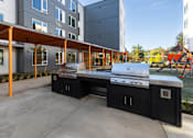 Thumbnail 13 of 38 - A BBQ grill is in the middle of a concrete patio.