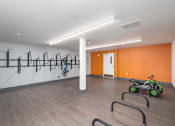 Thumbnail 18 of 38 - A gym with orange walls and a row of exercise bikes.