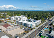Thumbnail 1 of 38 - A large white building with a glass facade is surrounded by a parking lot and other buildings.