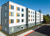 Thumbnail 3 of 38 - A row of modern buildings with grey, white and orange panels.