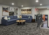 Thumbnail 34 of 35 - A blue couch is in the middle of a room with a grey carpet.