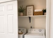 Thumbnail 18 of 21 - A white door opens to a small laundry room with a washer and dryer.