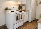 Thumbnail 17 of 21 - A white kitchen with a stove, oven, and refrigerator.