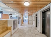 Thumbnail 4 of 21 - A long hallway with a wooden ceiling and tile flooring.