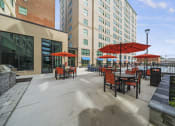 Thumbnail 23 of 76 - a patio with tables and umbrella  at The Icon, Richmond, VA, 23230s and a building in the background at The Icon in Richmond, VA 23230