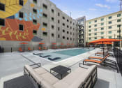 Thumbnail 47 of 76 - a pool with lounge chairs and umbrellas in front of a building at The Icon in Richmond, VA 23230