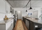 Thumbnail 57 of 76 - a kitchen with white cabinets and a large island with granite countertops at The Icon, Richmond, VA 23230