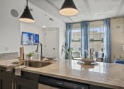 Thumbnail 61 of 76 - a kitchen counter with a sink and dishwasher next to a living room with a couch and  at The Icon, Richmond, VA, 23230