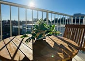 Thumbnail 16 of 18 - A wooden table with a plant on it sits on a balcony with a view of the city.