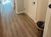 Thumbnail 10 of 18 - A hallway with a white door and a basket on the floor.