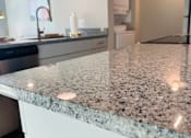 Thumbnail 18 of 18 - A granite countertop with a stainless steel dishwasher in the background.