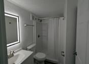 Thumbnail 13 of 25 - A white bathroom with a toilet, sink, and shower.