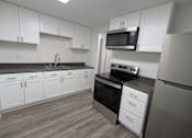 Thumbnail 22 of 25 - A kitchen with white cabinets and a black oven.