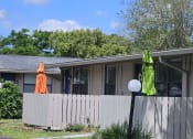 Thumbnail 9 of 33 - a house with a fence and two umbrellas in front of it