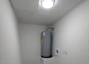 Thumbnail 14 of 25 - A room with a grey floor and a grey water heater on the wall.