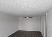 Thumbnail 15 of 25 - A room with a ceiling fan and wooden flooring.