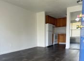 Thumbnail 7 of 21 - an empty living room with wood floors and a kitchen