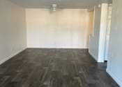 Thumbnail 11 of 21 - an empty living room with wood floors and a ceiling fan