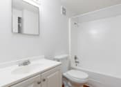 Thumbnail 13 of 24 - A white bathroom with a toilet, sink, and mirror.