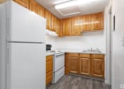 Thumbnail 12 of 24 - A white refrigerator is in a kitchen with wooden cabinets.