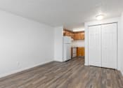 Thumbnail 9 of 24 - A room with a white door and a kitchen in the background.