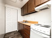 Thumbnail 34 of 43 - A small kitchen with a white stove and wooden counter.