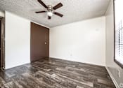 Thumbnail 31 of 43 - A room with a ceiling fan and wood flooring.