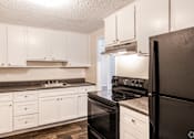 Thumbnail 42 of 54 - A kitchen with black appliances and white cabinets.