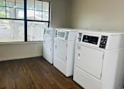 Thumbnail 30 of 32 - an empty laundry room with four washers and dryers and a window