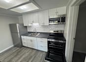 Thumbnail 5 of 32 - A kitchen with white cabinets and a black stove top oven.