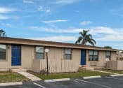 Thumbnail 1 of 16 - a small tan building with two blue doors and a fence