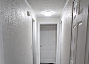 Thumbnail 7 of 33 - A long hallway with a white door at the end.