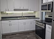 Thumbnail 4 of 33 - A kitchen with white cabinets and a black stove top oven.