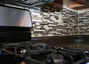 Thumbnail 13 of 21 - a stove top oven in a kitchen with a tile wall