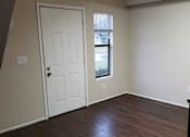 Thumbnail 10 of 11 - an empty living room with wooden floors and a white door