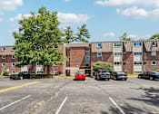 Thumbnail 21 of 44 - A parking lot with cars and apartment buildings in the background.