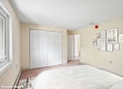 Thumbnail 44 of 44 - A bedroom with a white bed and a wall of pictures.