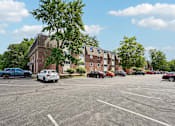 Thumbnail 20 of 44 - A parking lot with cars and a building in the background.
