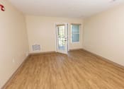 Thumbnail 7 of 16 - A room with wooden flooring and a door leading to another room.