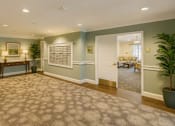 Thumbnail 16 of 16 - A hallway with a carpeted floor and a white door leading to a living room.