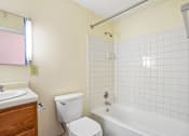 Thumbnail 43 of 44 - A white toilet sits next to a white bathtub in a bathroom.