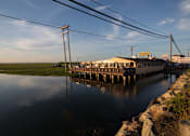 Thumbnail 14 of 19 - A long pier extends into a body of water with a building on it.