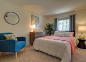 Thumbnail 4 of 19 - A bedroom with a bed, a blue chair, and a plant.