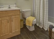 Thumbnail 6 of 19 - A bathroom with a wooden vanity and a white toilet.