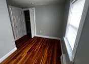 Thumbnail 4 of 7 - A room with wooden floors and a white door.
