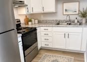 Thumbnail 23 of 26 - A kitchen with a refrigerator, sink, and cabinets.
