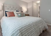 Thumbnail 9 of 35 - A bed with a white comforter and pillows in a room.