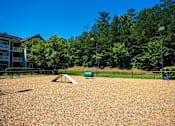 Thumbnail 30 of 35 - A playground with a seesaw and a slide in the middle of a sandy area.