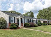 Thumbnail 6 of 24 - A row of houses with green lawns and trees in the background.