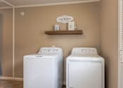 Thumbnail 11 of 24 - Two white front load washing machines in a laundry room.